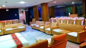 Una habitación de hotel con zona de estar, un escenario y un ventanal grande.