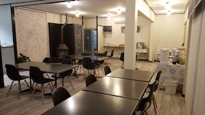 A modern dining area with multiple tables and chairs, a map on the wall, and a kitchen area in the background. - Town House Motor Inn (Young)