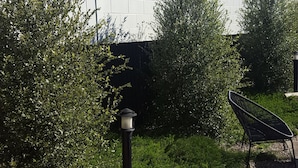 A garden area with a white brick wall, a black lamp post, and a black chair. - Town House Motor Inn (Young)