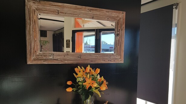A white console table with a vase of flowers, a mirror, and a small figurine. - Town House Motor Inn (Young)