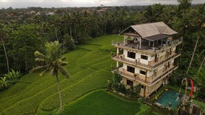 A multi-story building with a balcony, surrounded by lush greenery and a pool. - Nirwa Ubud Karma (Ubud)
