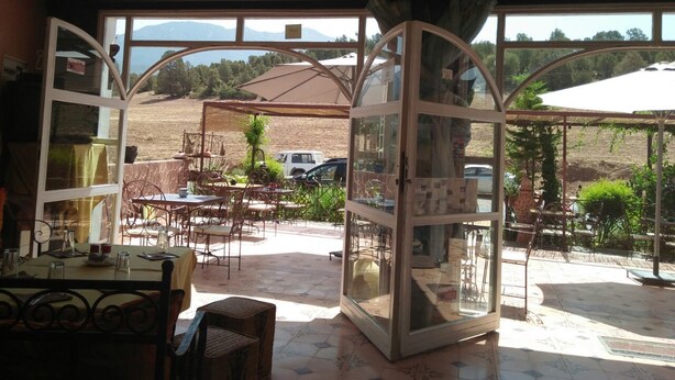 Comedor de concepto abierto con vistas al campo, que cuenta con asientos exteriores y un ventanal grande.