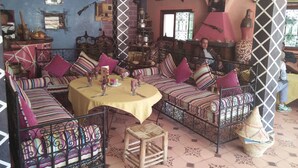 Un salón acogedor y bien decorado con sofás estampados, una mesa redonda dispuesta para comer y diversos objetos decorativos.