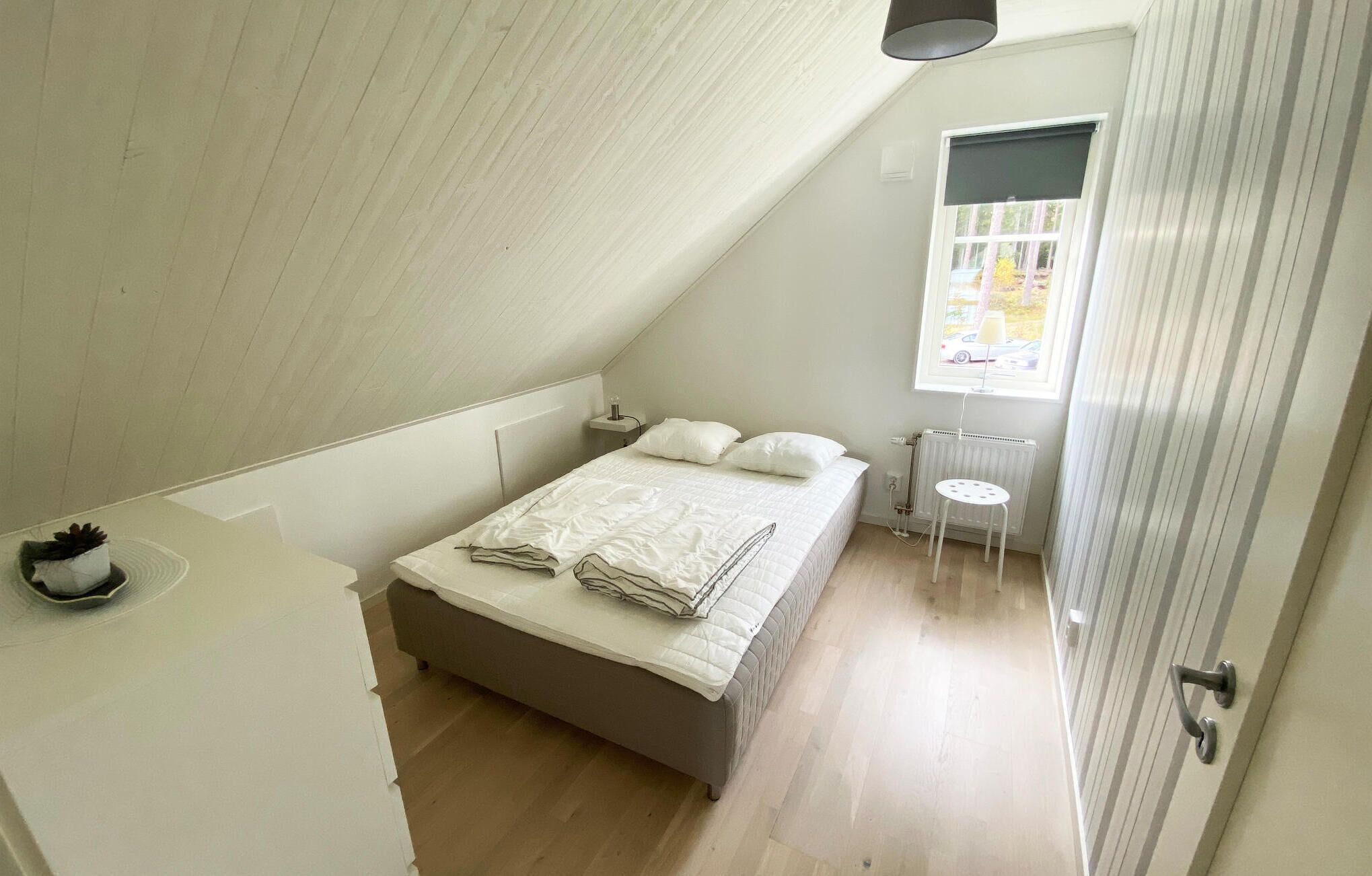 Un dormitorio con cama, mesita de noche y una pequeña ventana.