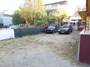 Asuinalue, jossa on sorapäällysteinen ajotie, parkkeerattuja ajoneuvoja ja aidattu puutarha.