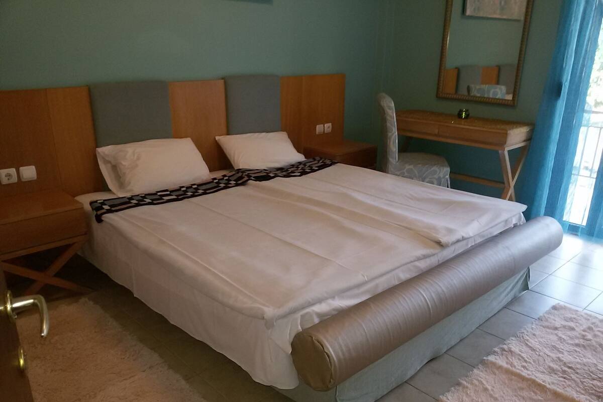 A neatly made bed with a patterned bedspread, a wooden headboard, and a bedside table with a lamp.