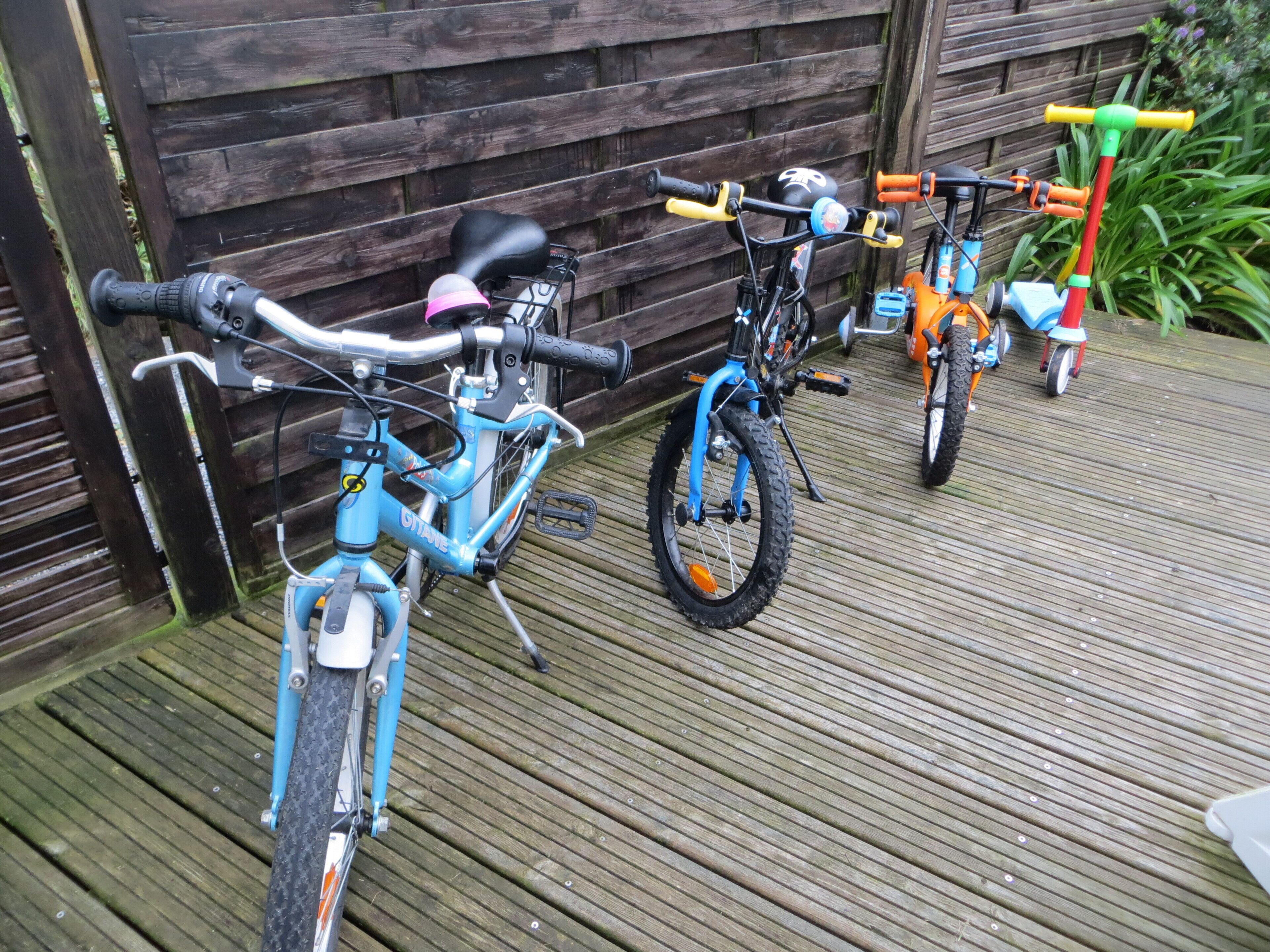 A wooden deck with two bicycles parked against a wooden fence.