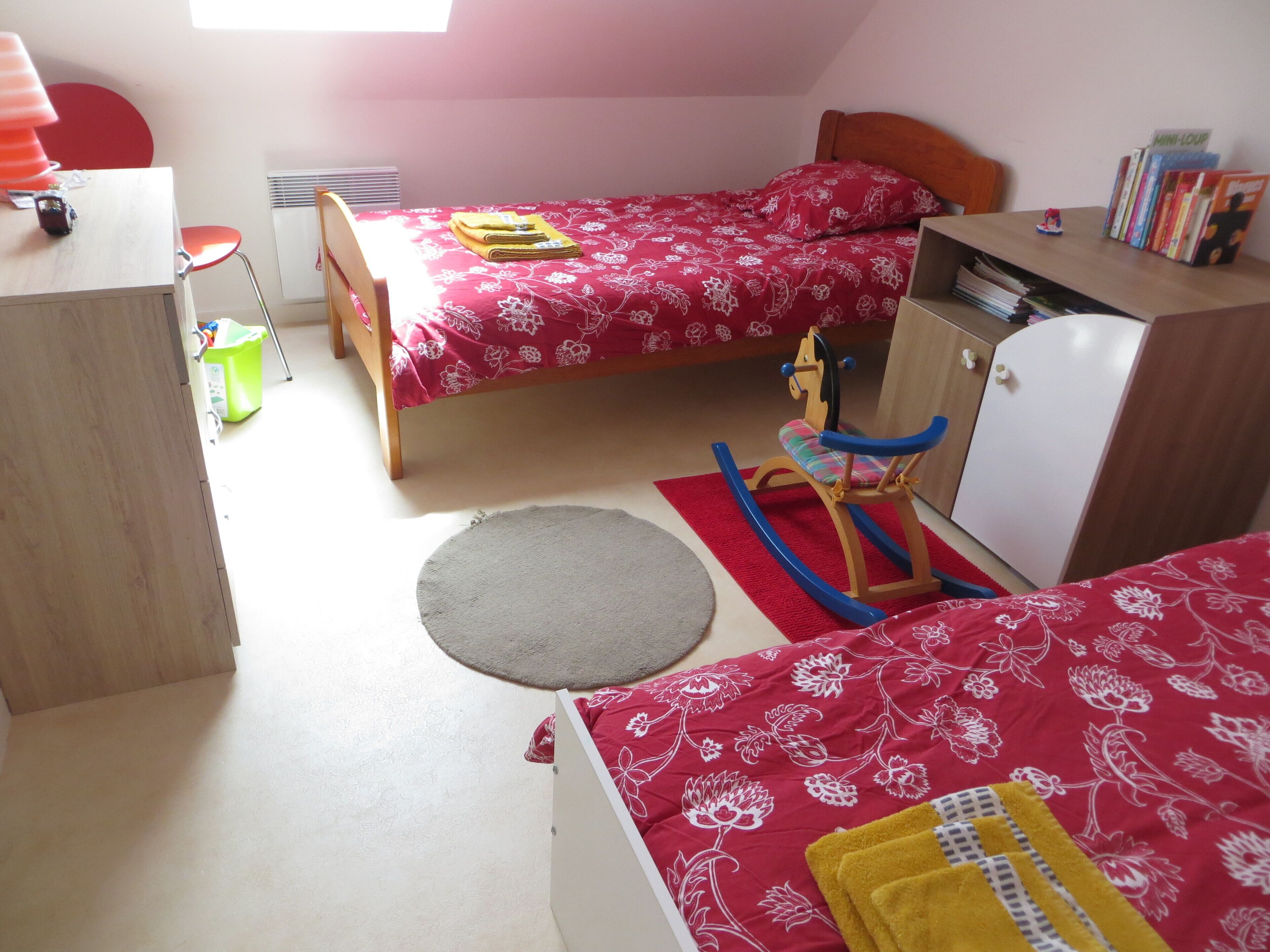 Un dormitorio con dos camas, un escritorio, una silla, un armario y un radiador.