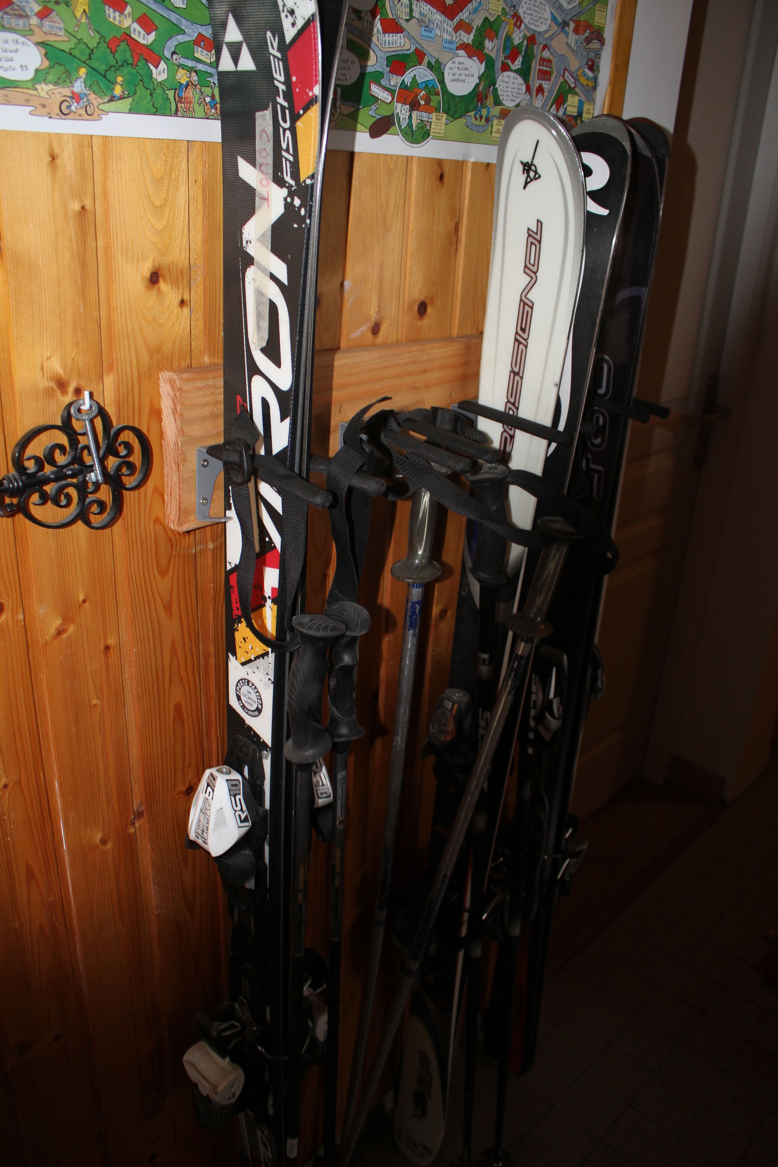 Een houten wand met ski's en stokken die ertegen leunen.