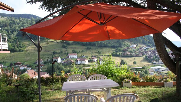 A table and chairs under an umbrella, overlooking a village. - BEAUTIFUL VIEW APARTMENT 50 M2, 2 Bedrooms, 1 shower room, 4 people. (La Bresse)