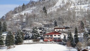 A snow-covered landscape with buildings, including a two-story house with a red roof and a smaller building with a white facade. - BEAUTIFUL VIEW APARTMENT 50 M2, 2 Bedrooms, 1 shower room, 4 people. (La Bresse)