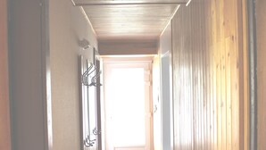 A hallway with wooden walls, a tiled floor, and a door at the end leading to a bright room. - BEAUTIFUL VIEW APARTMENT 50 M2, 2 Bedrooms, 1 shower room, 4 people. (La Bresse)