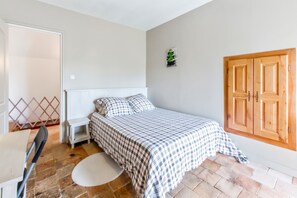 Ein Schlafzimmer mit einem Bett, einem kleinen Nachttisch, einer Wandleuchte, einer Holztür und einem Fenster.