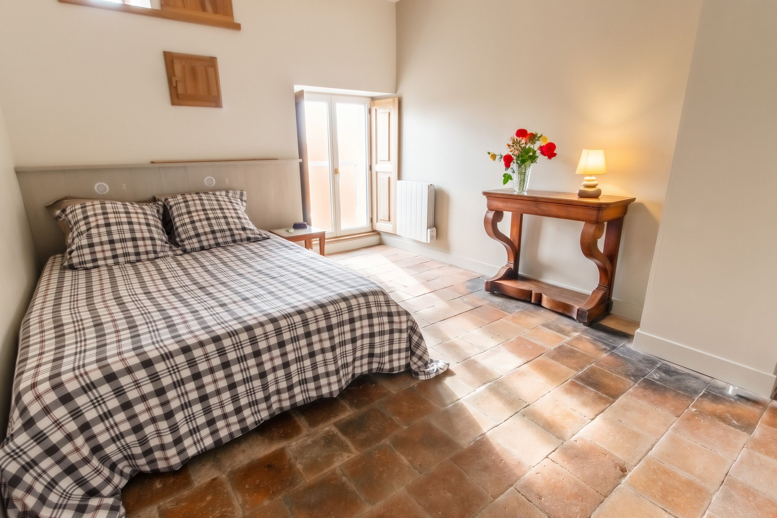 Une chambre à coucher avec un lit, une table de chevet avec une lampe, un radiateur et une fenêtre.