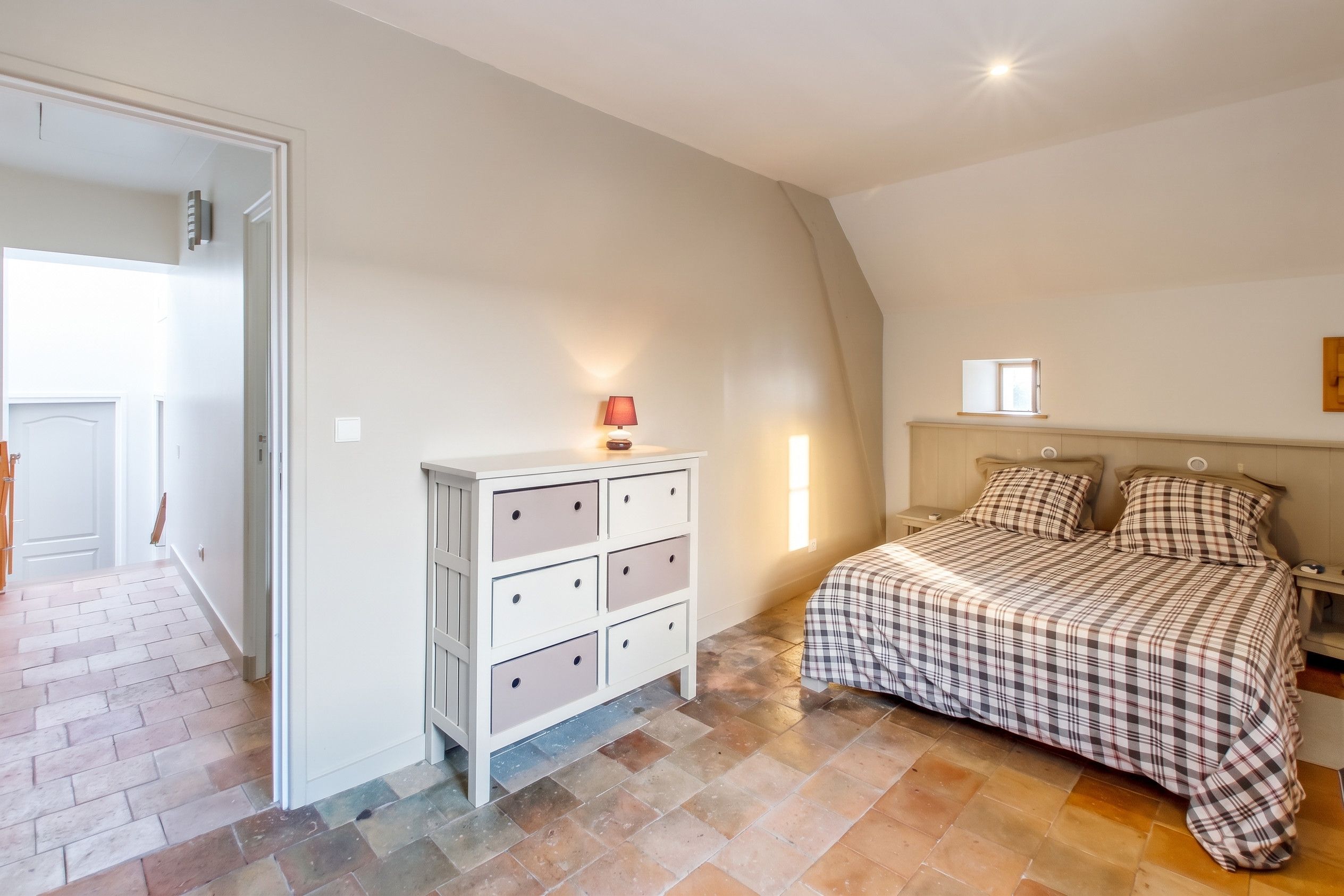 A bedroom with a bed, a dresser, a nightstand, and a window.