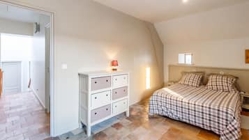 A bedroom with a bed, a dresser, a nightstand, and a window.