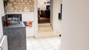 A modern kitchen with a stone wall, a built-in bench, and a tiled floor.