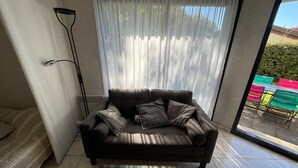 Una sala de estar moderna con un sofá marrón oscuro, una mesa de centro de cristal y cortinas translúcidas.
