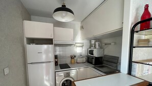Una cocina funcional equipada con refrigerador, lavadora, microondas y tostadora.
