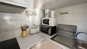Una cocina compacta equipada con microondas, tostadora, cafetera y lavamanos.