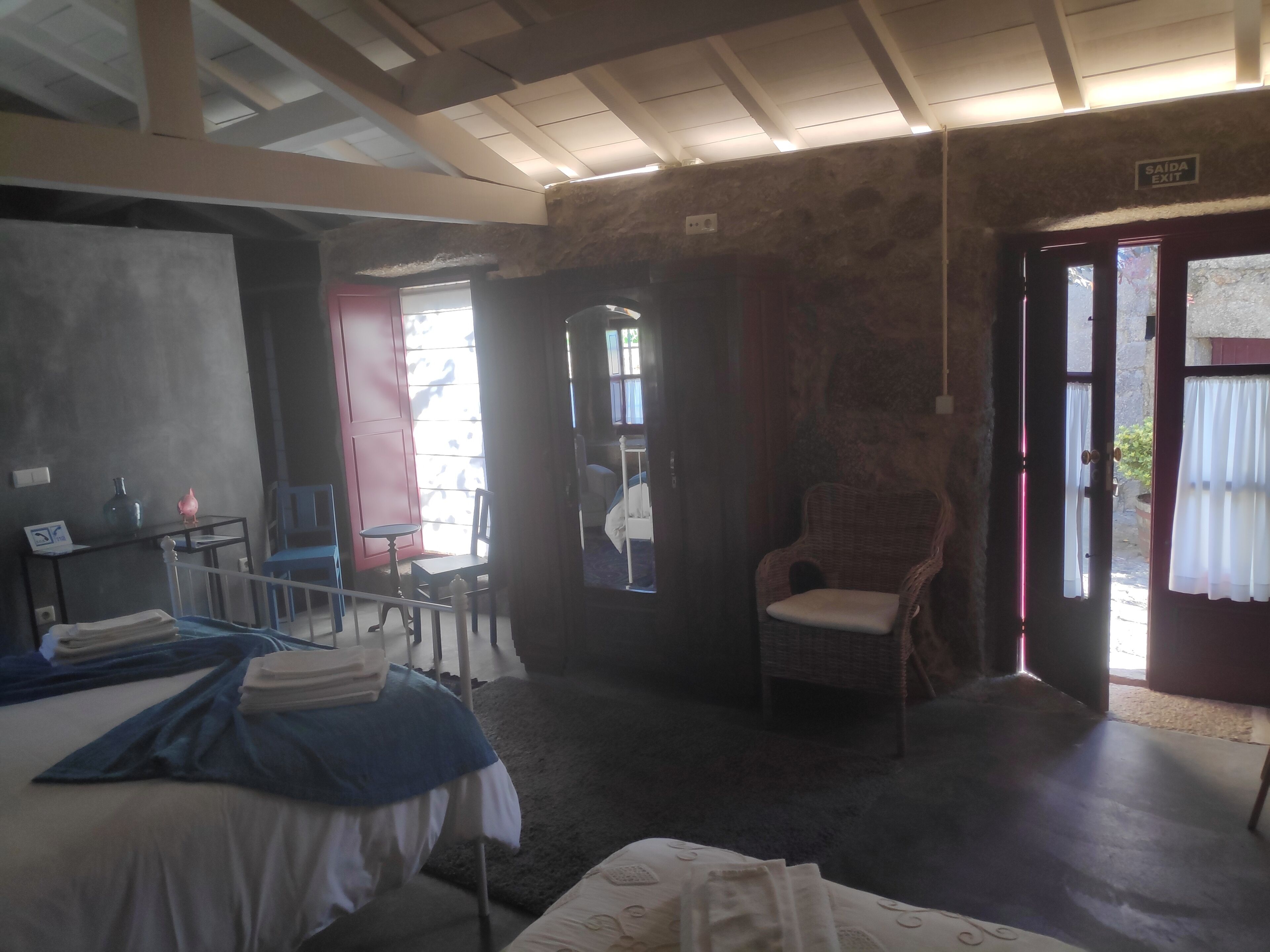 A room with a bed, a chair, a table, and a door leading outside.