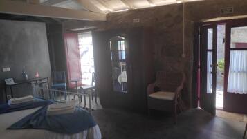 A room with a bed, a chair, a table, and a door leading outside.
