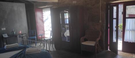 Una habitación con una cama, una silla, una mesa y una puerta que da al exterior.