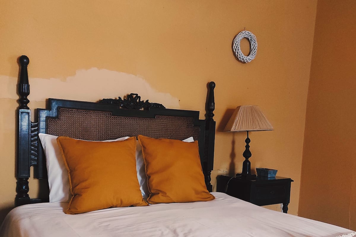 A bed with a wooden headboard, two mustard-colored pillows, and a white bedspread.