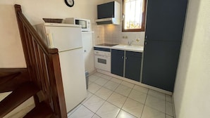 A compact kitchen with a refrigerator, microwave, stove, and cabinets.