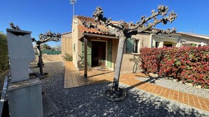 A building with a tiled roof, a door, and a small garden area with gravel and plants.