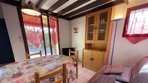 A cozy room with a dining table, wooden chairs, a sofa, and a cabinet.