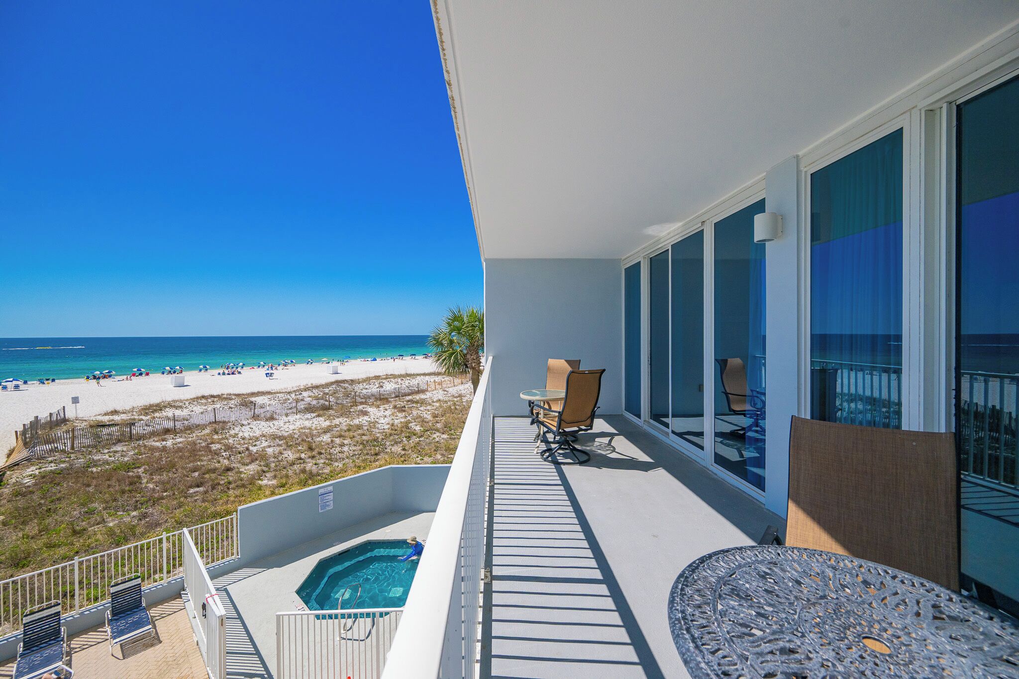 Un balcón con piscina, mesa y sillas con vista a la playa.