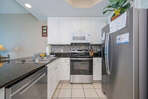 A modern kitchen with white cabinets, a stainless steel refrigerator, a microwave, an oven, and a sink. - LIGHTHOUSE! One Bedroom XTRA BATH! Low Floor Beach Front (Gulf Shores)