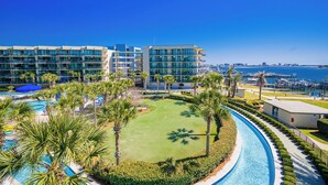 Un resort con piscina, palmeras y un puerto deportivo al fondo.