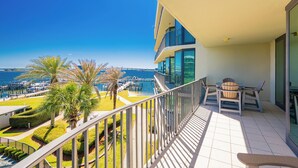 Un balcón con vista al mar, una mesa con sillas y una palmera.