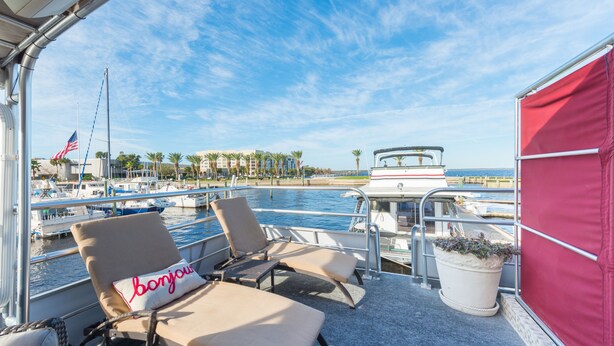 A boat deck with lounge chairs, a potted plant, and a view of the marina and beach. - NOT YOUR TYPICAL HOUSEBOAT: 60 FEET OF FUN! (Sanford)