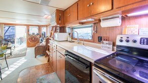 A compact RV kitchen with wooden cabinets, a stove, a sink, and a dishwasher. - NOT YOUR TYPICAL HOUSEBOAT: 60 FEET OF FUN! (Sanford)