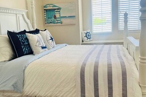 Uma cama bem arrumada com roupa de cama listrada, cabeceira e almofadas decorativas.