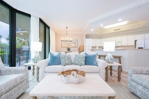A modern living room with a sofa, two armchairs, a coffee table, and a chandelier. - Spend Vacation on the Bay!  Phoenix on the Bay 1116 (Orange Beach)