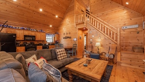 A cozy cabin interior with a living room, kitchen, and a wooden staircase. - Deep Creek Gem w/ Indoor Hot Tub (OAKLAND)