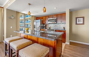 Une cuisine dotée d’un îlot central, de meubles en bois, d’un four à micro-ondes et d’un réfrigérateur.