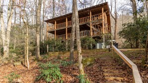 A wooden cabin with a balcony, surrounded by trees and a wooden staircase leading up to it. - Draggin Fly- Romantic Getaway! River Frontage - Hot Tub - Firepit (Vilas)