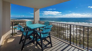 Ein Balkon mit Tisch und Stühlen, der Blick auf einen Strand und den Ozean bietet.