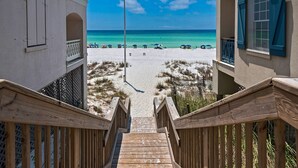 A wooden staircase leading to a beach with a flag, sandy beach, and clear blue sky. - Splash Pad⛳️Complimentary Golf Cart & New Pool 2026 | Sleeps 13 (Miramar Beach)