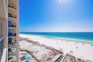 Een hoog hotel met balkons met uitzicht op een strand.