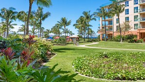 A resort with a well-maintained lawn, palm trees, and a building with multiple balconies.