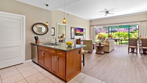 A spacious living area with a kitchen island, dining area, and a balcony with a view.