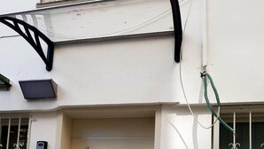 A white door with a metal handle, a small window with decorative bars, and a green garden hose on the right. - Royal Apartment Tel Aviv (Tel Aviv)
