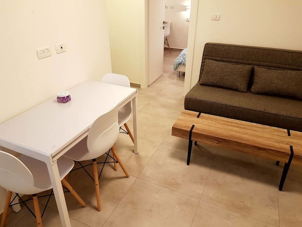 A room with a white table and chairs, a wooden bench, and a brown sofa.