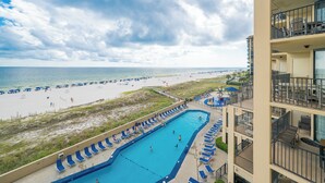 A hotel with a pool, beach view, and multiple balconies.